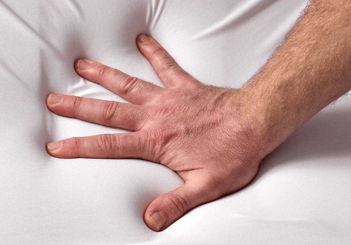 Hand pressing into soft breathable memory foam of the Restinator pillow