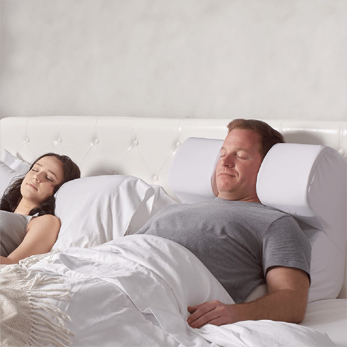 The Snorinator® pillow being used by a husband in bed with his partner