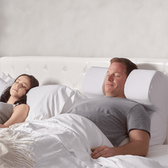 The Snorinator® pillow being used by a husband in bed with his partner